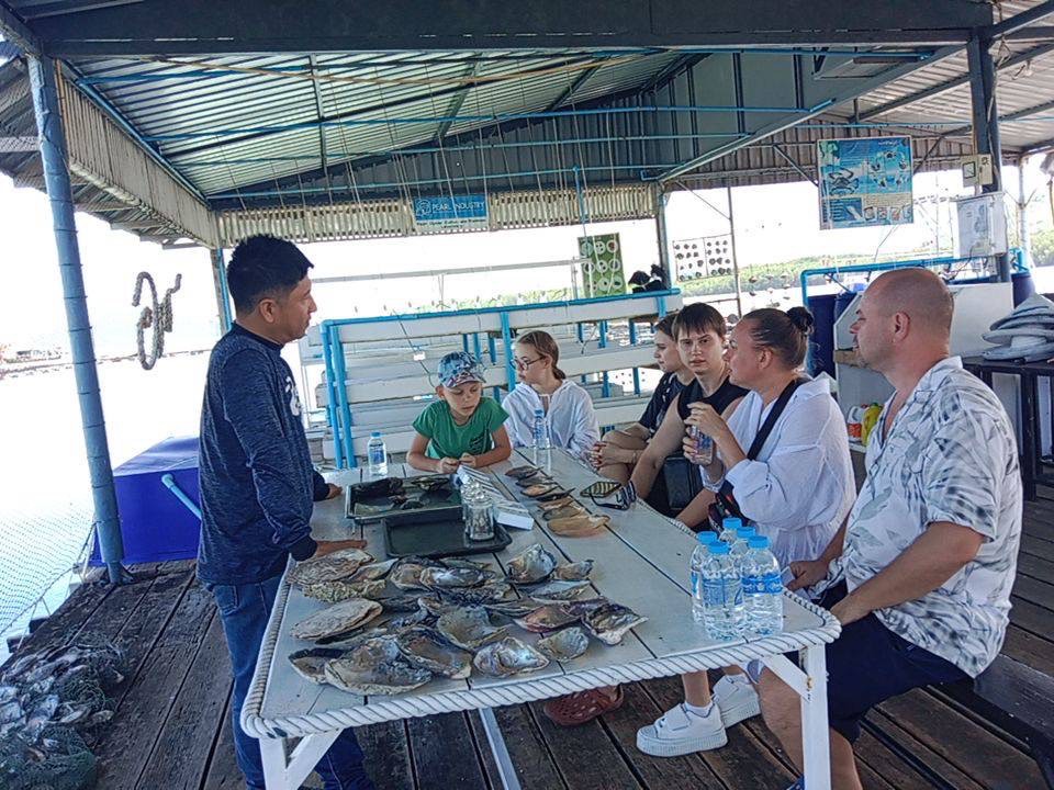 A tour guide explaining how pearl farming works to a family