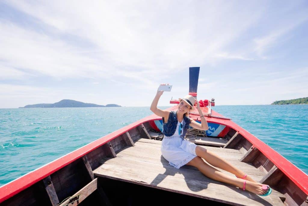 A woman soaking up the sun on a longtail boat in Phuket before her beach club party
