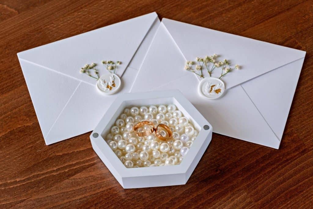 A box of pearls beside wedding invitations. Pearls aren’t necessarily taboo at weddings.