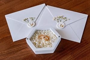 A box of pearls beside wedding invitations. Pearls aren’t necessarily taboo at weddings.