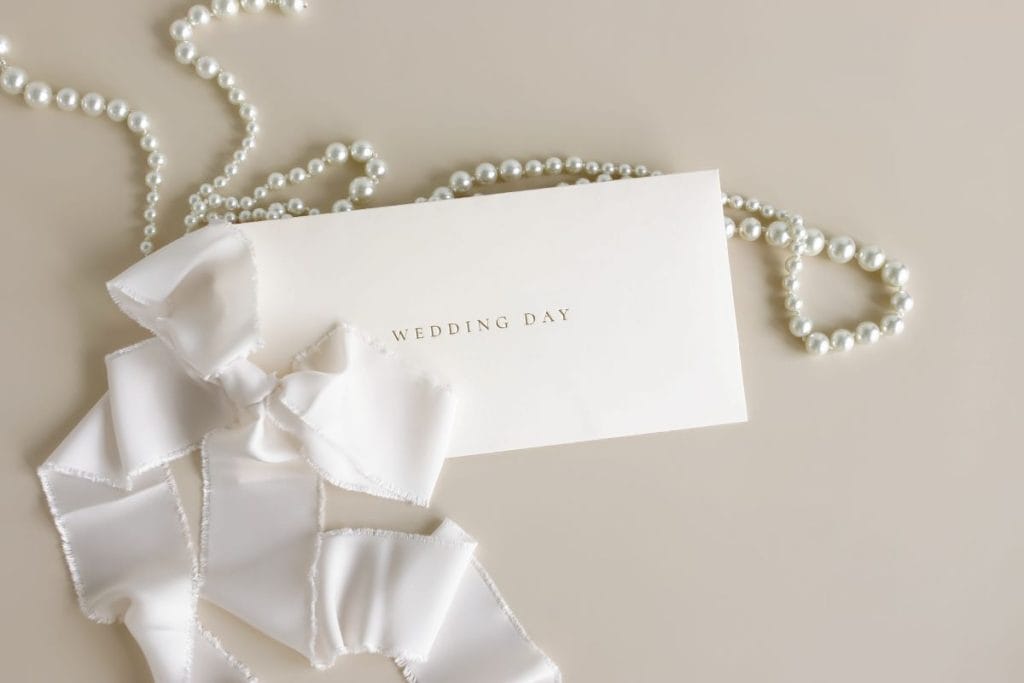 A wedding invitation with a necklace of pearls paired with a ribbon